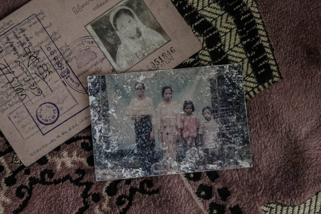 Identity card of Meena* with a family photograph, placed on a prayer rug. While her son was persecuted in the Rakhine State, she managed to escape with her daughter-in-law and grandson in 2017. *Name changed